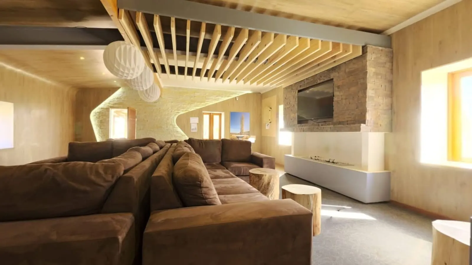 Timber lined lounge with slatted ceiling, deep sofas and a stone fireplace wall