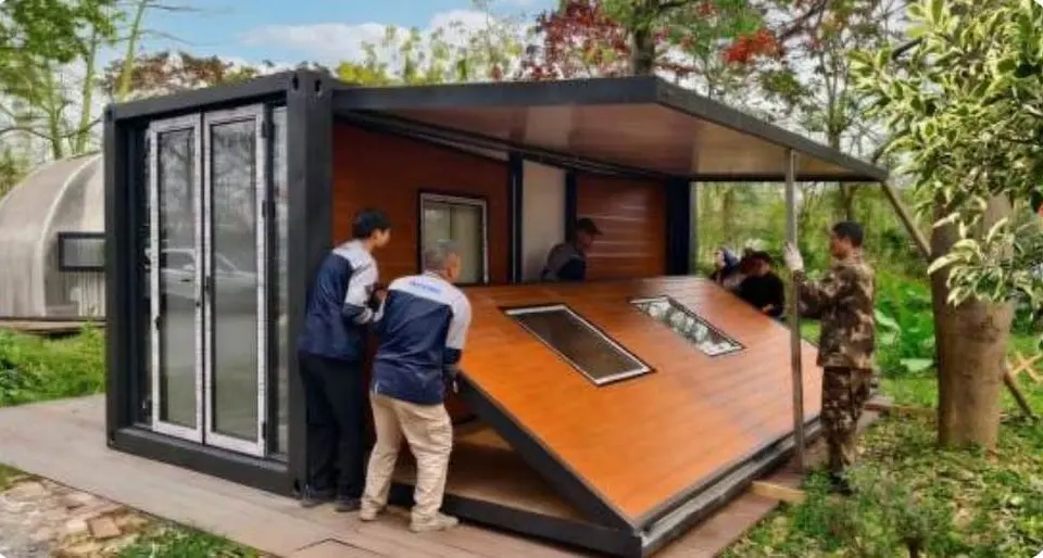 Installers unfolding the side room of an expandable house on site