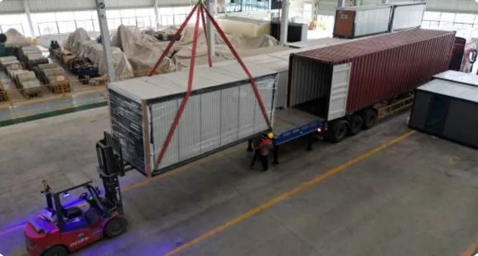 Folded expandable house being loaded into a shipping container by forklift