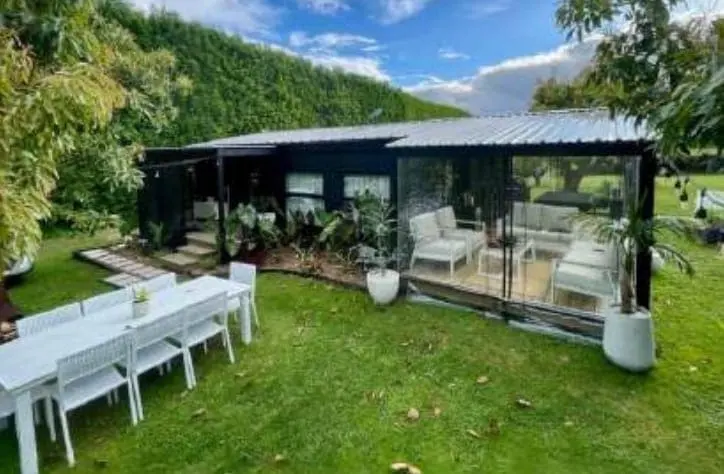 Black expandable cabin with outdoor dining set in a garden