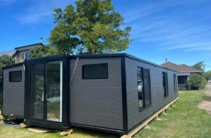 Dark expandable house on a residential lawn