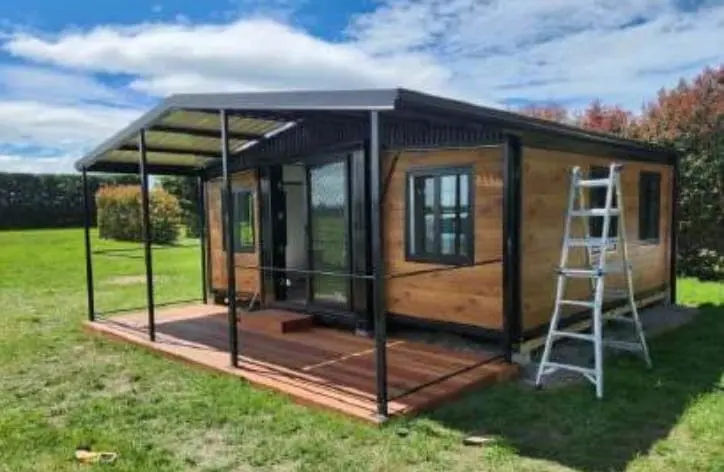 Timber clad expandable house with a covered deck